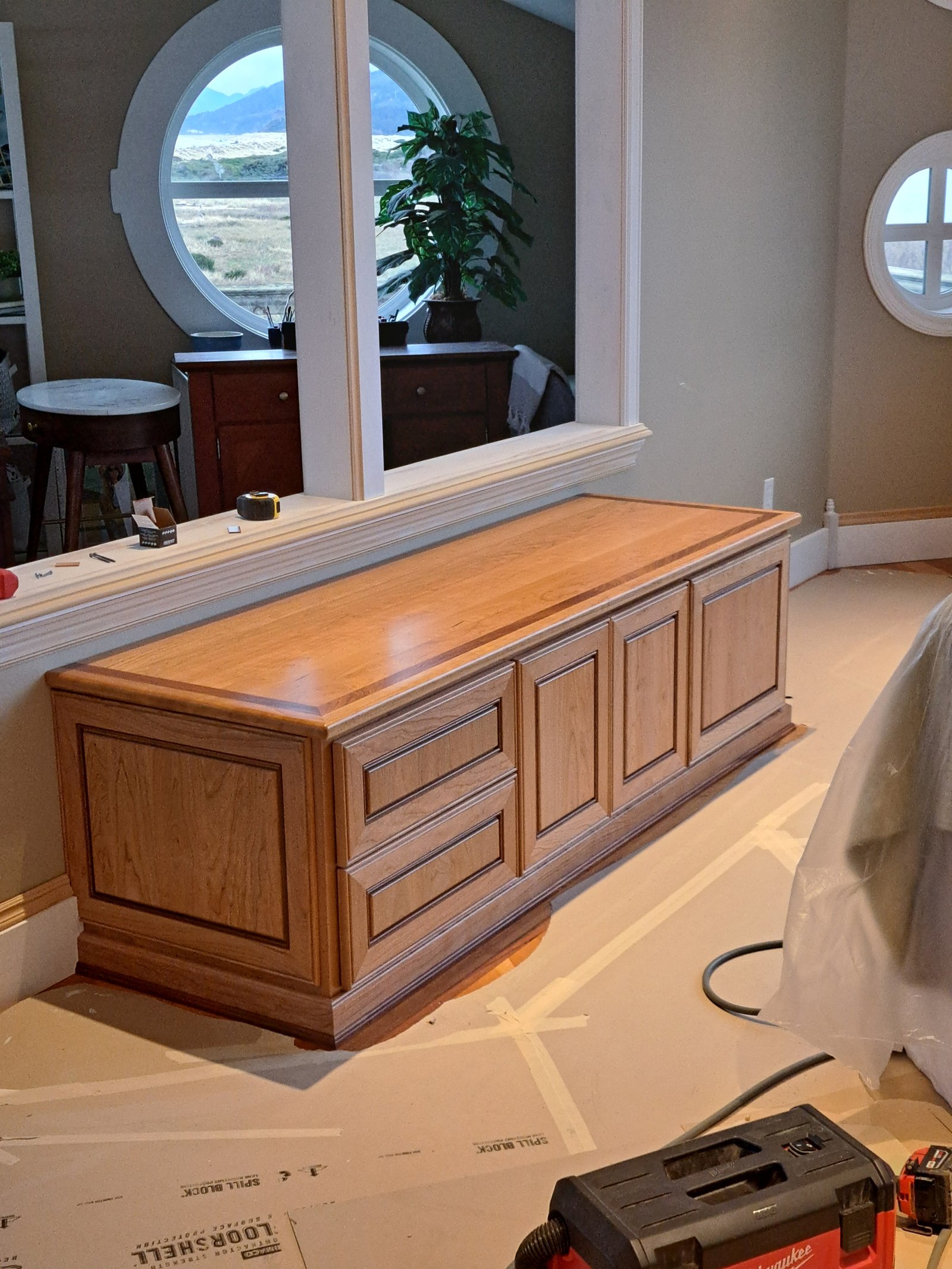 Cherry raised panel cabinet base during installation with round window behind