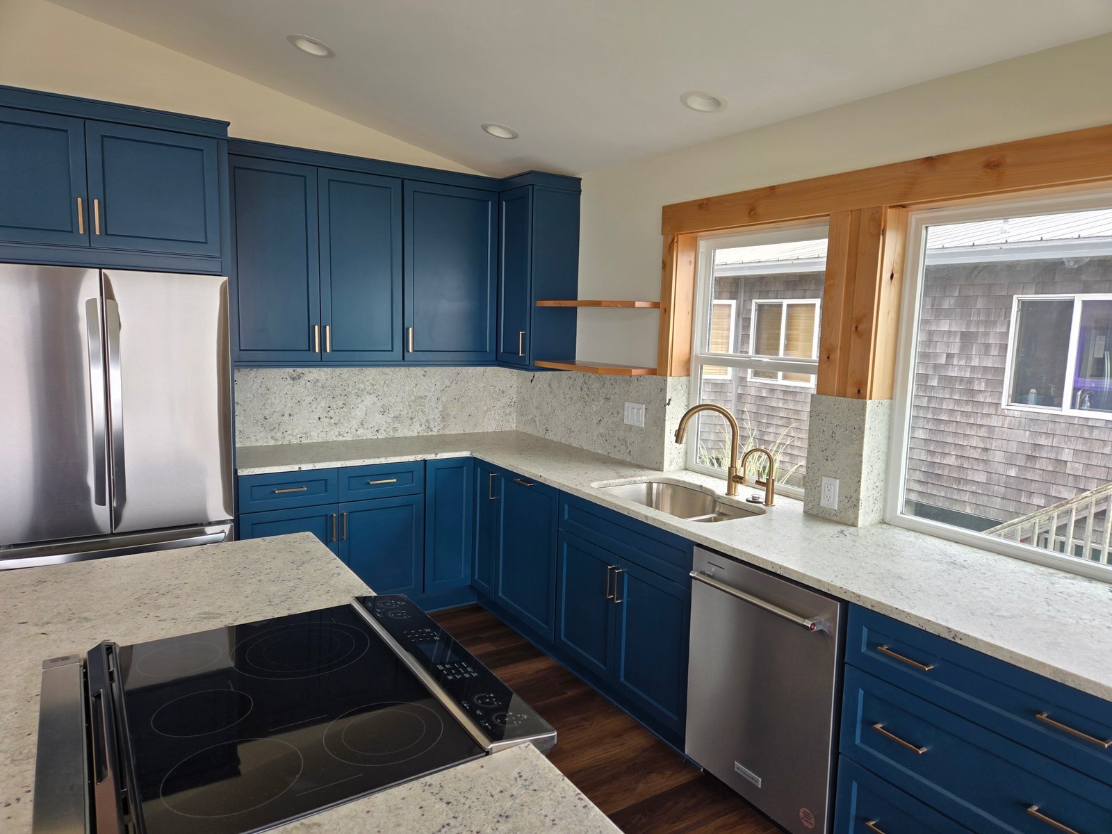 Completed blue kitchen with stove sink gold faucet and dishwasher